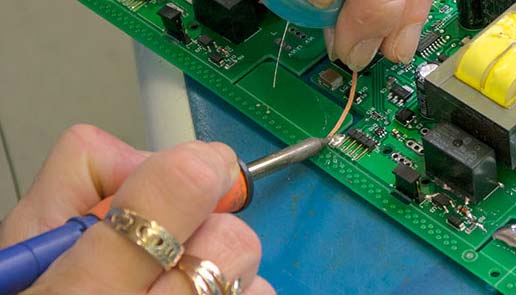 A worker soldering a circuit board